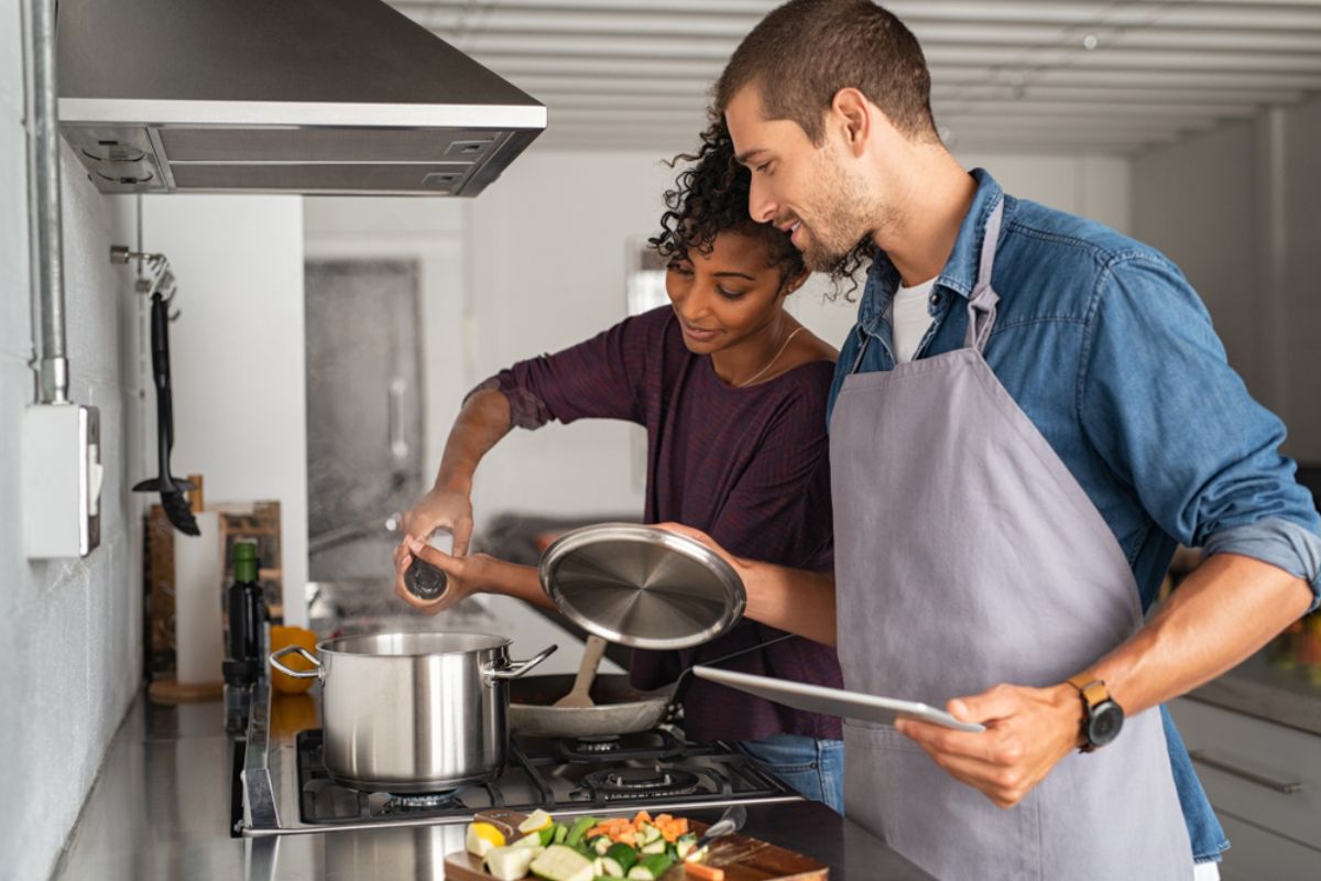 Coppia che cucina ed aggiunge del sale in pentola